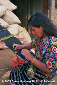 Pilar Gomez, Patzicía, kneels to weave on her back strap loom.  Pilar enjoys weaving and wearing styles from many different communities in Guatemala, not just her own.  Photo by Cheryl Guerrero 2005.