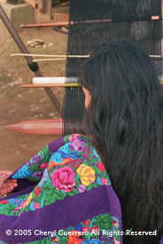 Pilar Gomez, Patzicía, weaves on a back strap loom from a pattern printed on a grid of a style traditionally associated with San Antonio Aguas Calientes.  Photo by Cheryl Guerrero 2005.