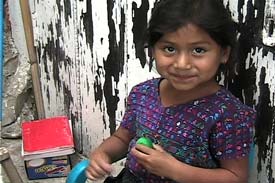 Graciela Panjoj Lopez, 6, winds thread on a paper bobbin for her mother to use in supplementary weft designs.  Photo by Kathleen Mossman Vitale 2004.