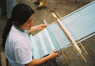 Lilian Elizabeth Cahuec Buv alternates bands of a twisted open weave with bands of plain weave, into which are added rows of ribbon.  She is weaving for Chilám, a European export organization. Photo by Margot Blum Schevill 2005.
